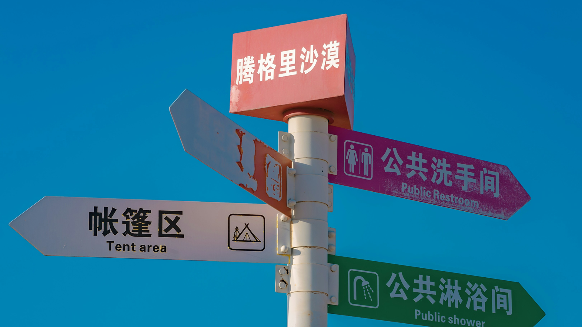Street scene in China with colourful Chinese-language wayfinding signage mounted on poles against a bright blue sky