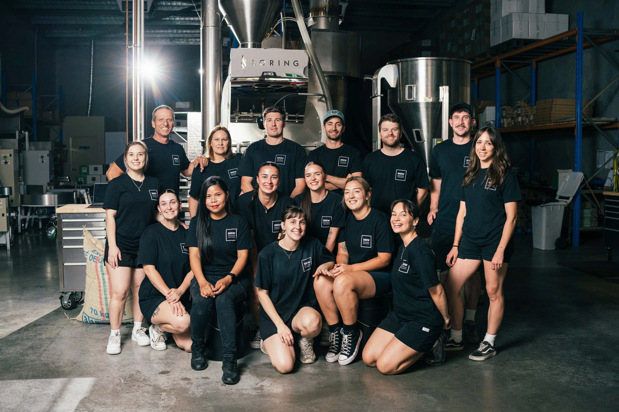Brew Coffee team photo showing staff in matching black uniforms posed in two rows
