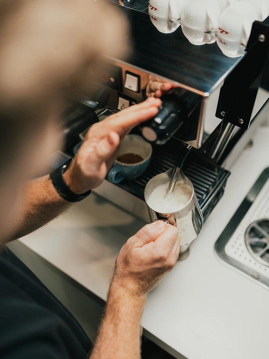 Close-up of a barista's hands operating a commercial espresso machine — Brew Coffee barista action photography