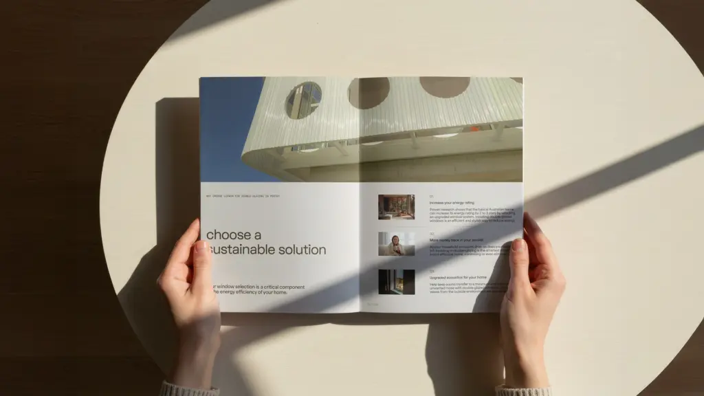 Person holding open a printed brochure revealing an architectural interior photography double-page spread