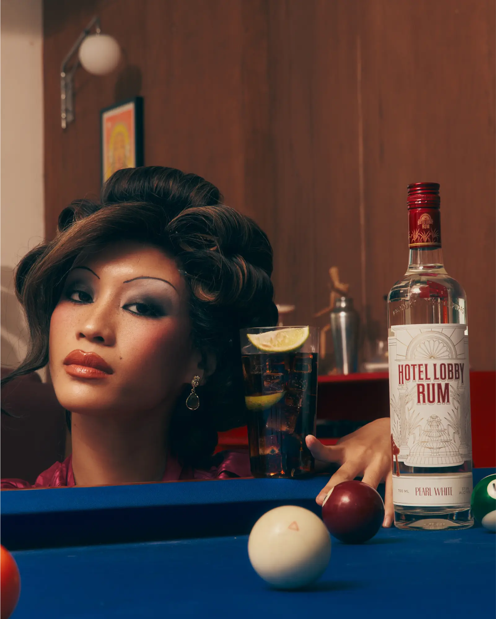 Glamorous woman with large curly hair at a bar with a Hotel Lobby Rum bottle