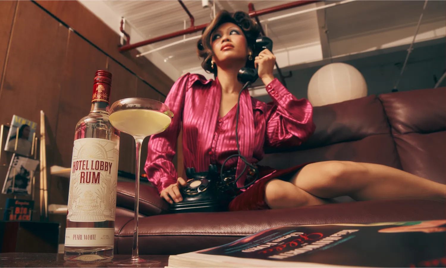 Woman in pink top posing with a Hotel Lobby Rum cocktail in a warm, atmospheric bar setting