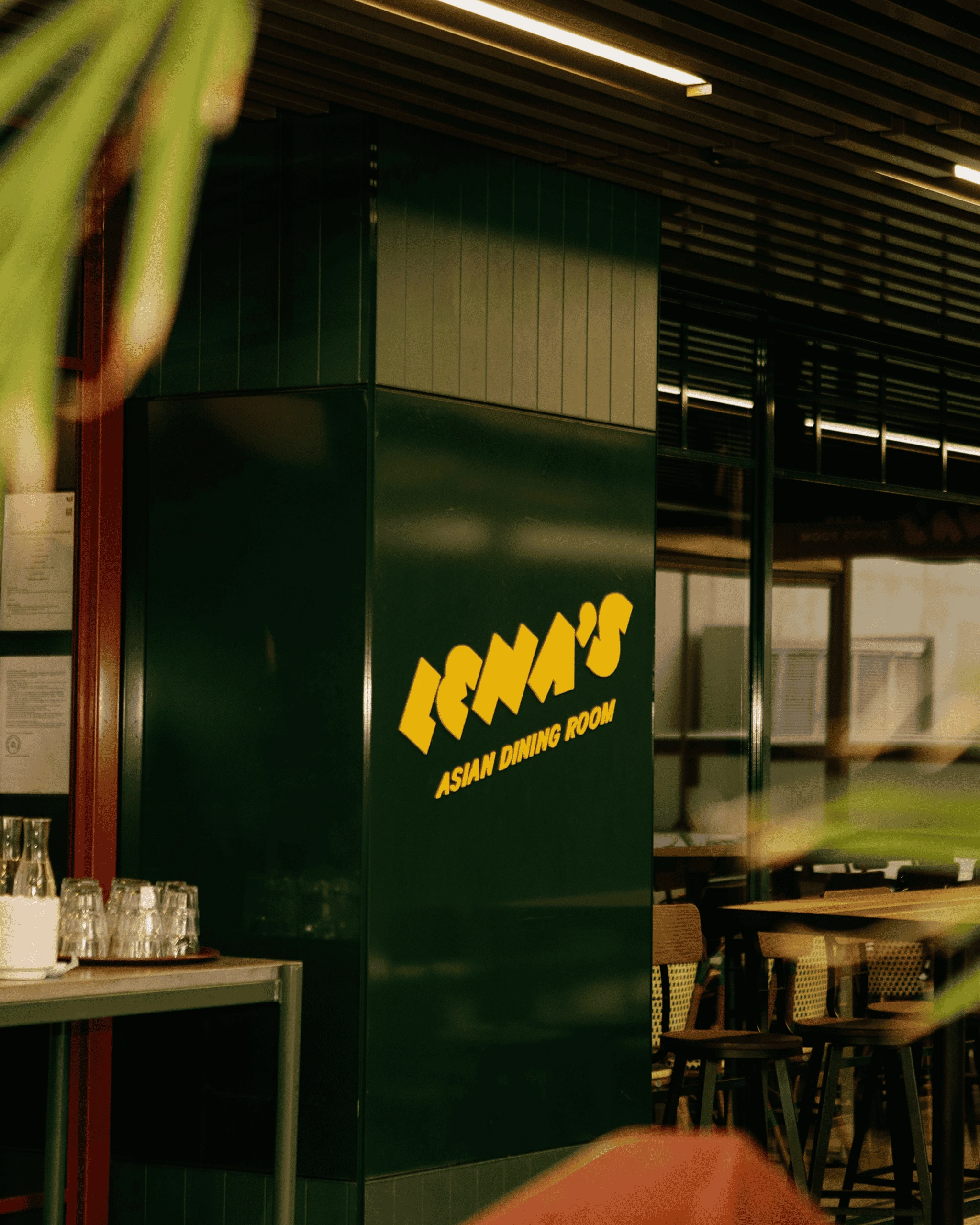 Intimate restaurant interior with dark green walls, wooden furniture and moody atmospheric lighting — Lena's restaurant photography