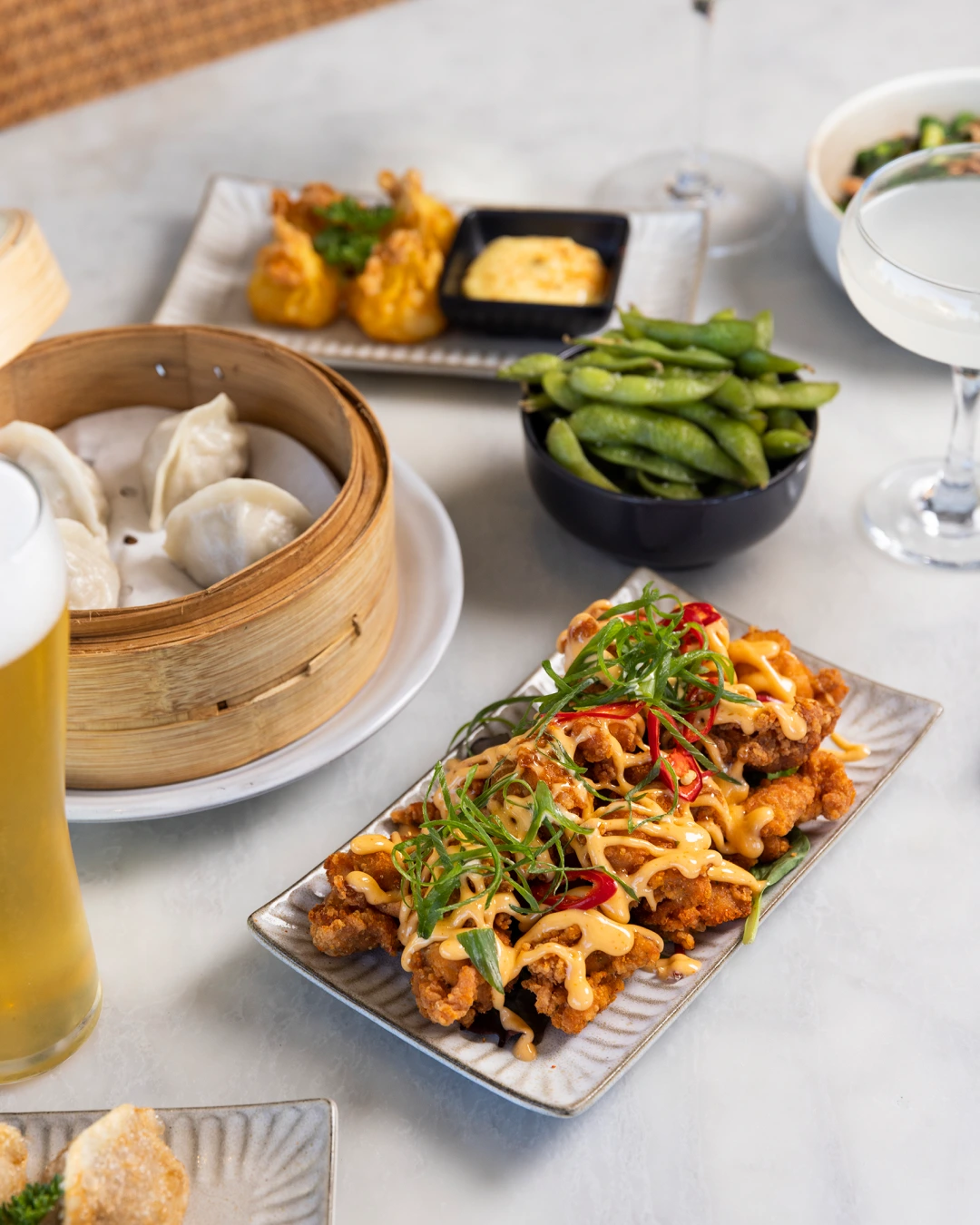 Overhead food photography showing a Miss Chow's dish with green vegetables and vibrant orange sauce served with chopsticks