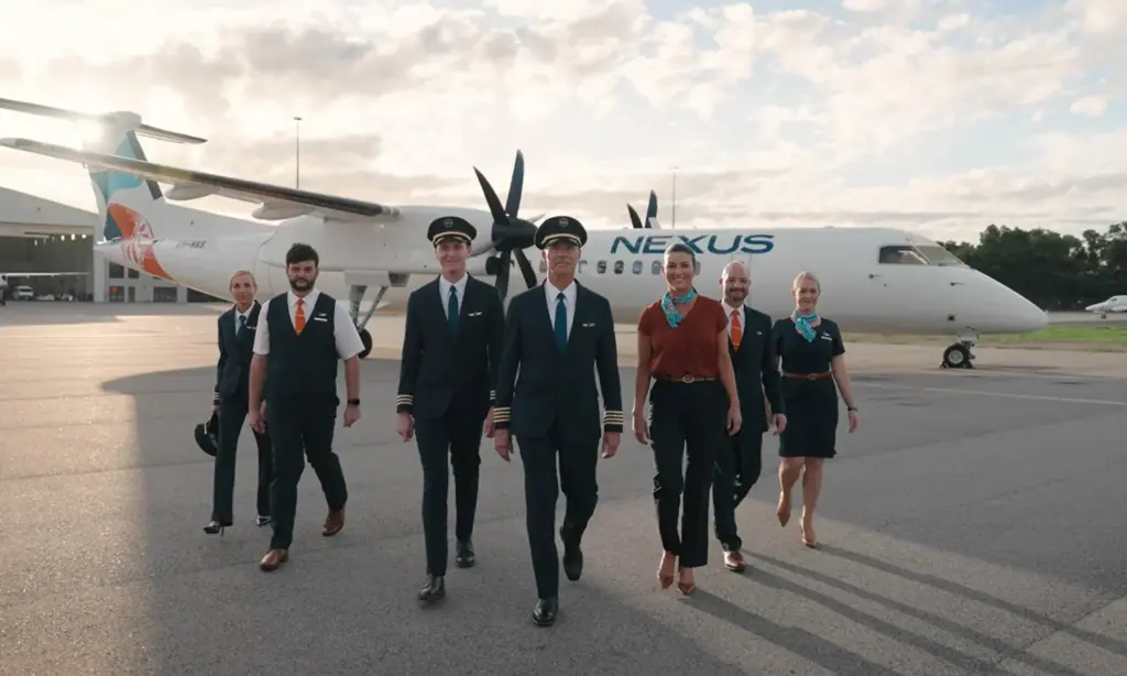Nexus Airlines crew members in uniform walking in formation in front of a branded aircraft on the tarmac