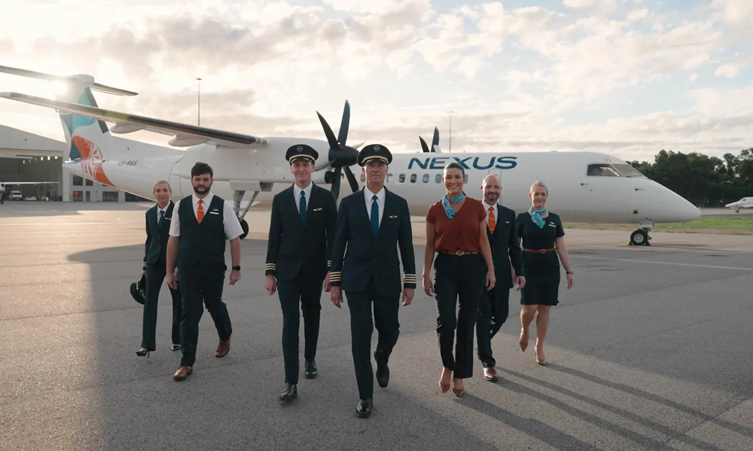 Nexus Airlines crew members in uniform walking in formation in front of a branded aircraft on the tarmac