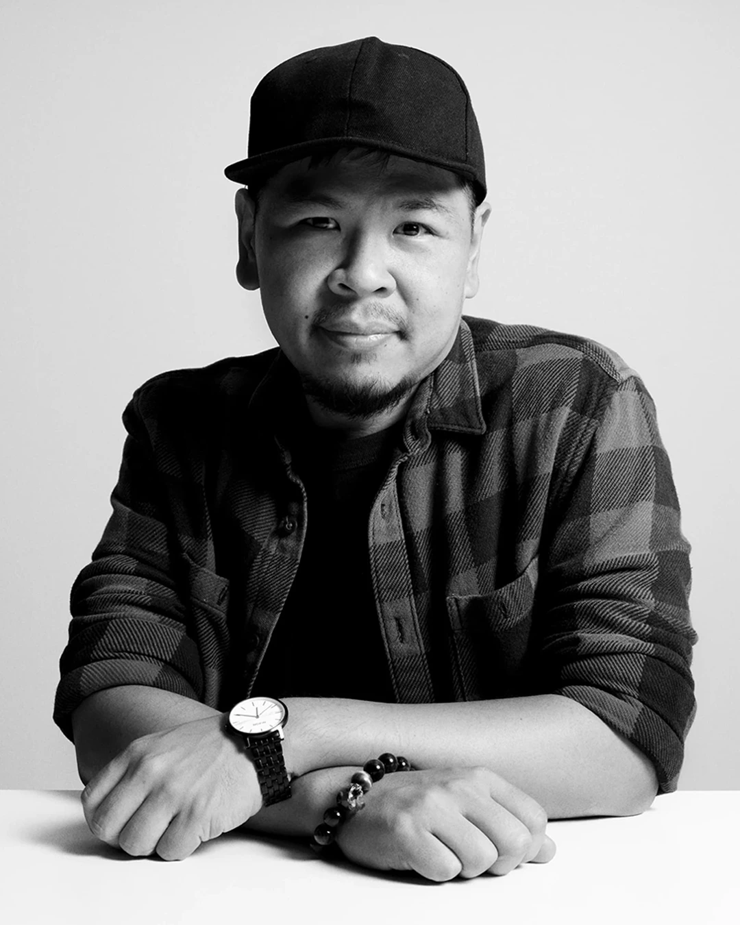 Black and white professional portrait of a man in dark clothing with arms crossed, looking directly at the camera