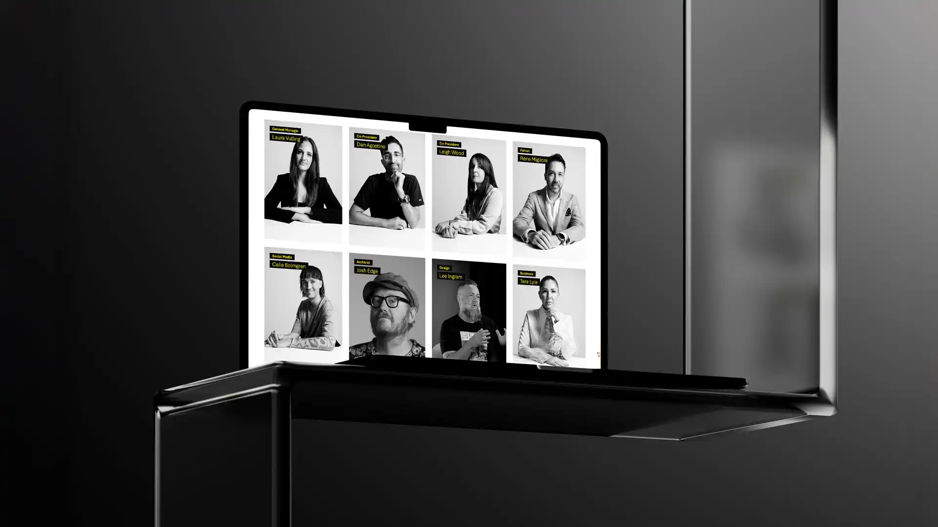 Laptop computer displaying the PADC website mockup showing a grid of black and white portrait photographs