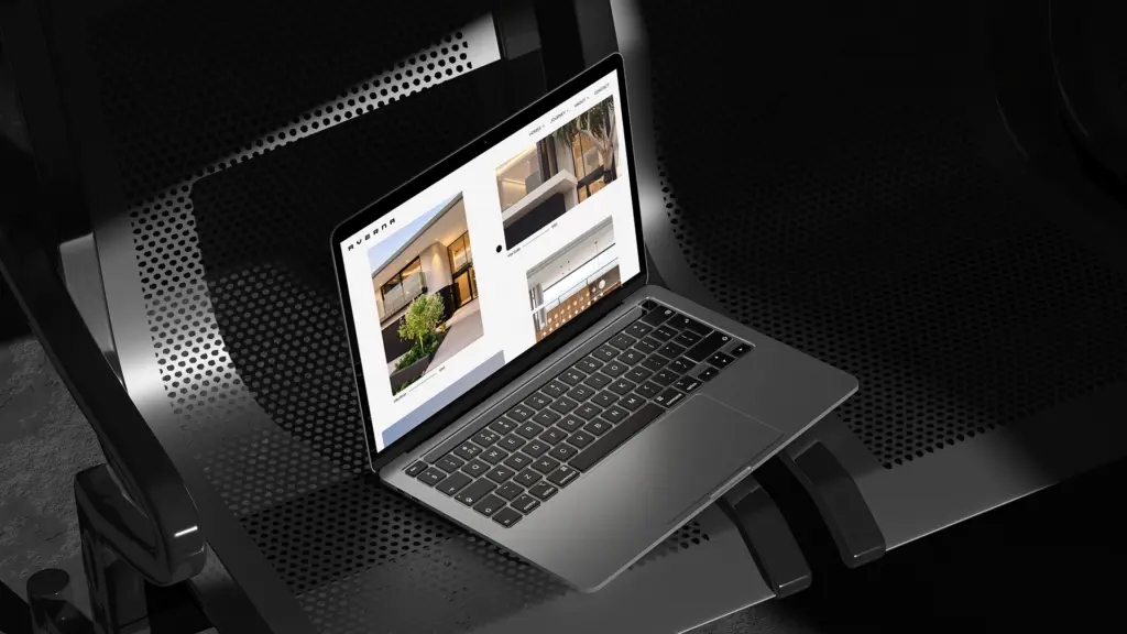 MacBook laptop viewed from above on a dark textured surface showing a website design