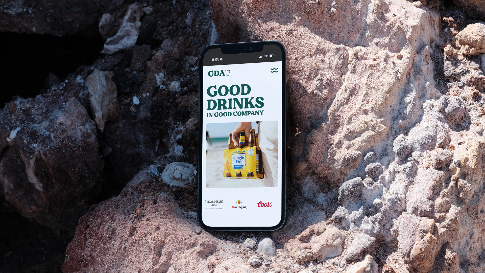 Smartphone held against a rocky coastal backdrop showing the Good Drinks Australia website