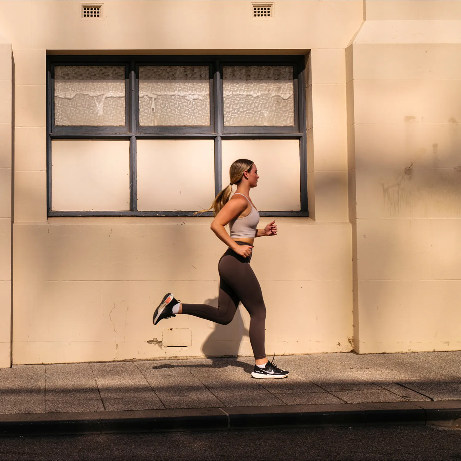 Person jogging with a dog on a city street in warm afternoon light