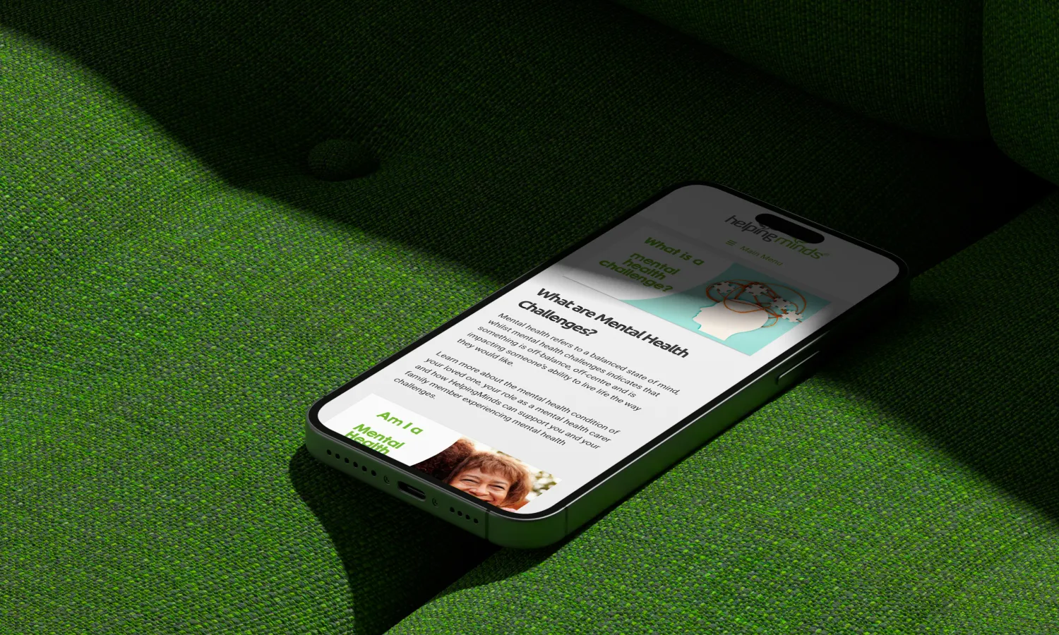 Smartphone on a green surface showing the HelpingMinds website design