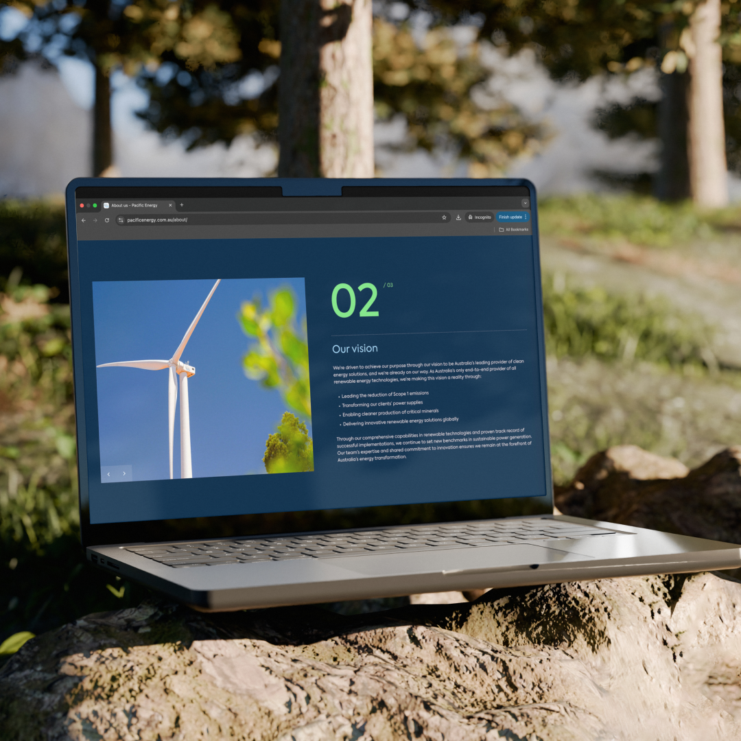 MacBook laptop outdoors with wind turbines visible in the background