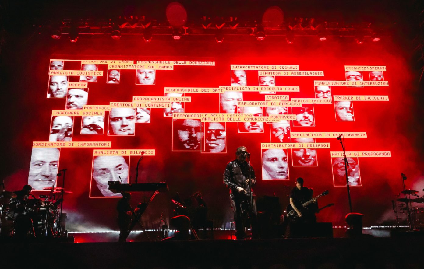 Massive Attack live show — performer on stage under dramatic red neon lighting