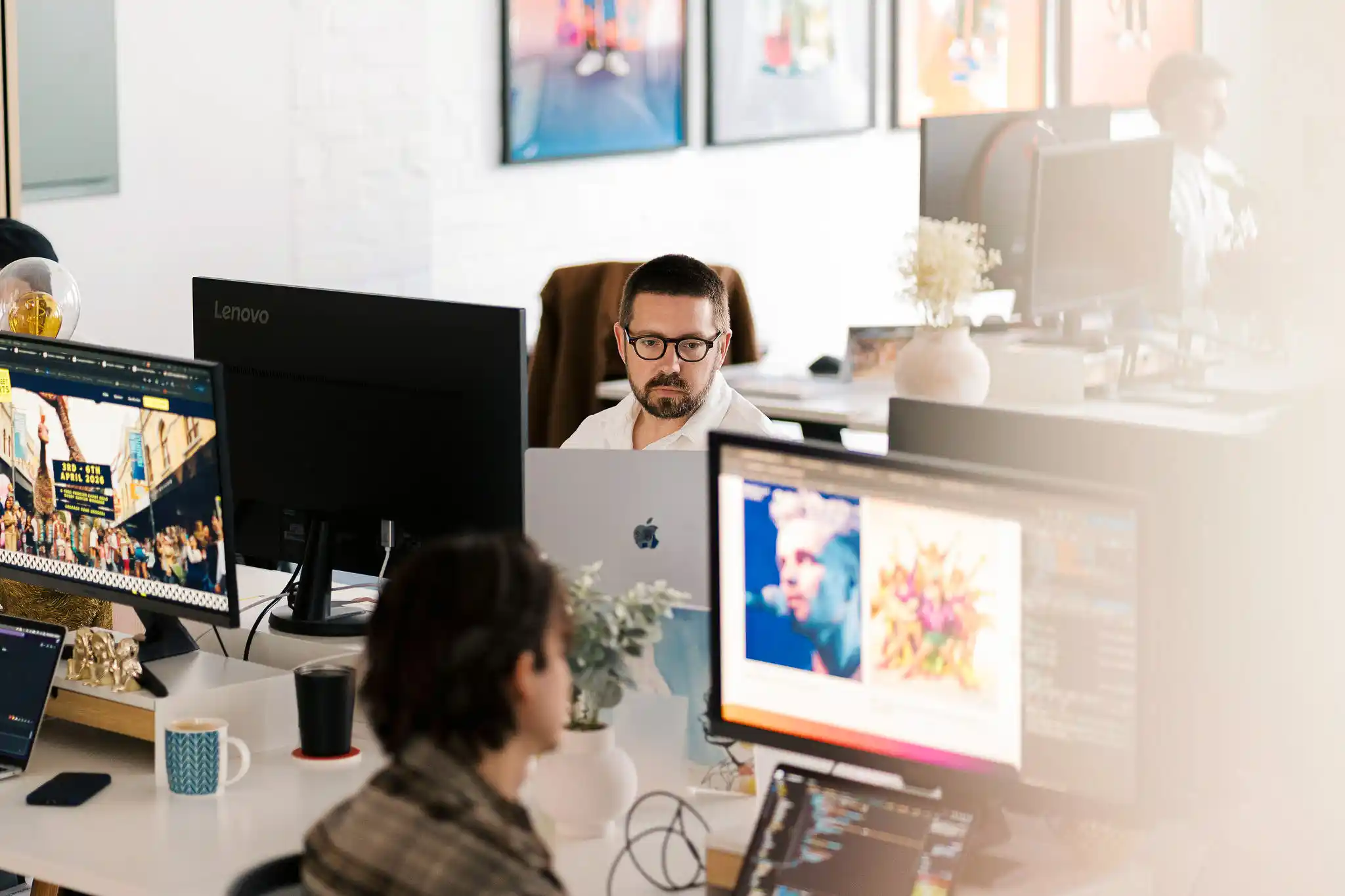 The Start team member working at a desk with a computer monitor showing design work — office candid, January 2026