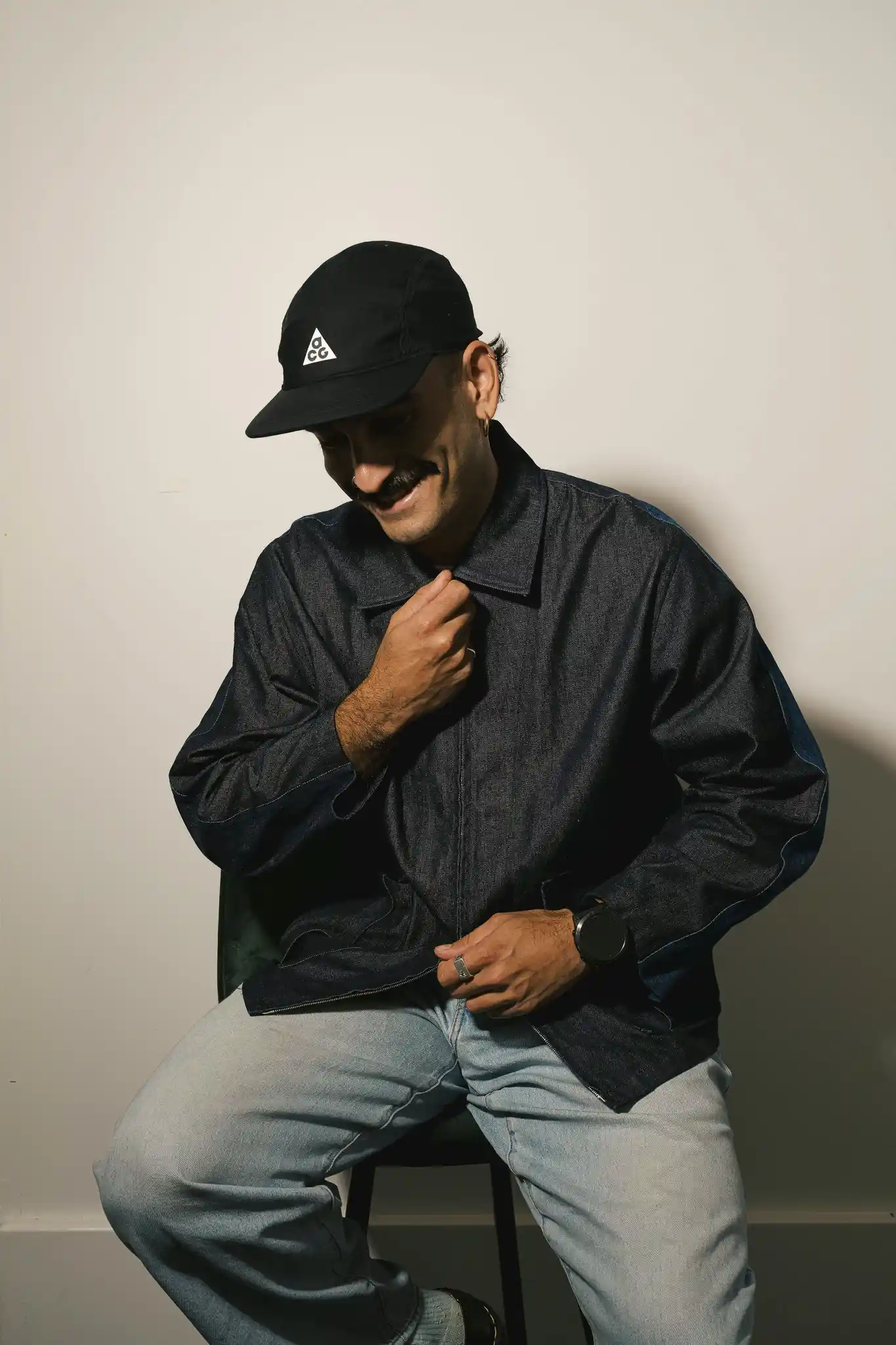 The Start team member wearing a dark cap and jacket, seated in a relaxed sideways pose — portrait photo, January 2026