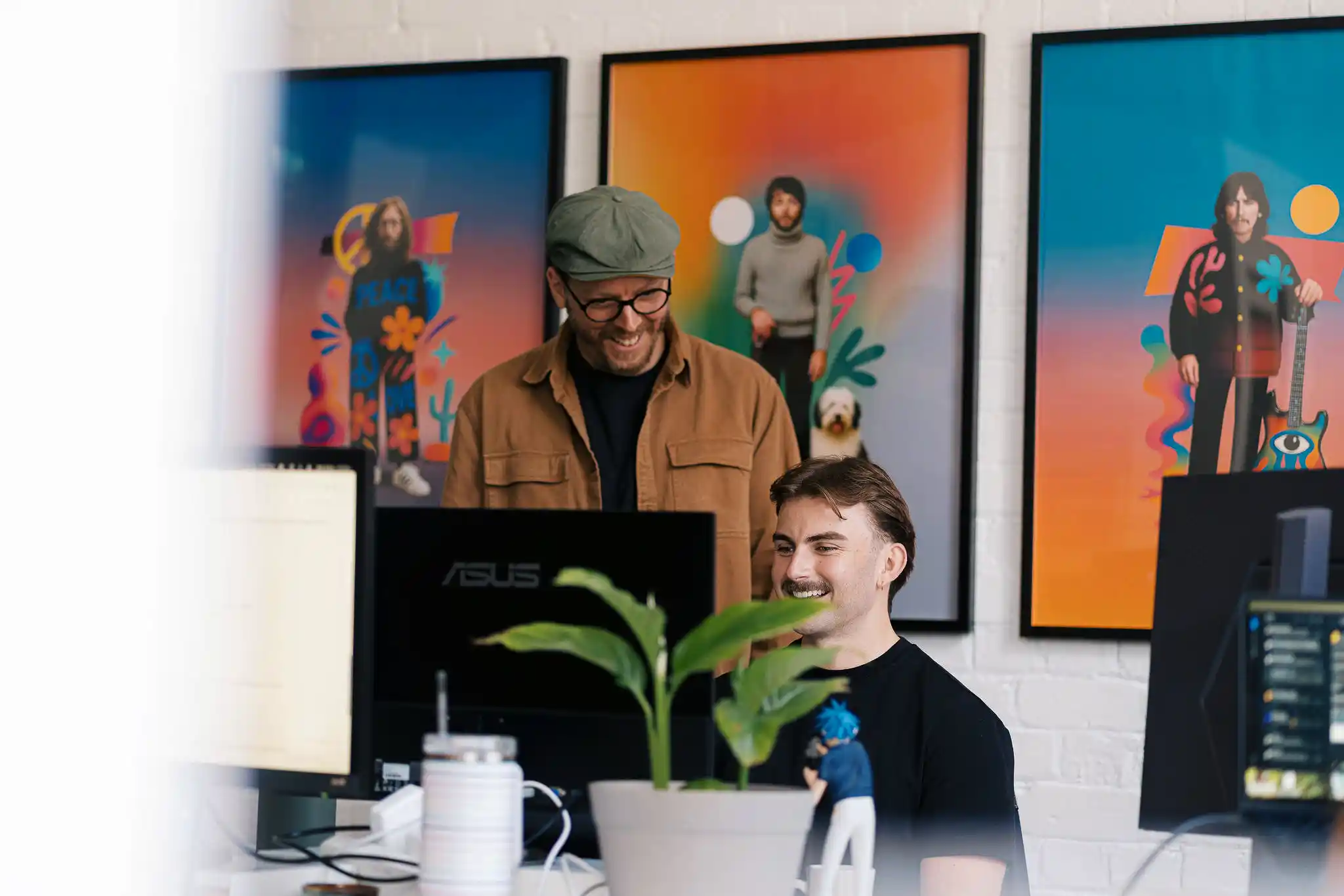 Three Start team members smiling in a bright creative studio with large colourful artwork prints on the walls