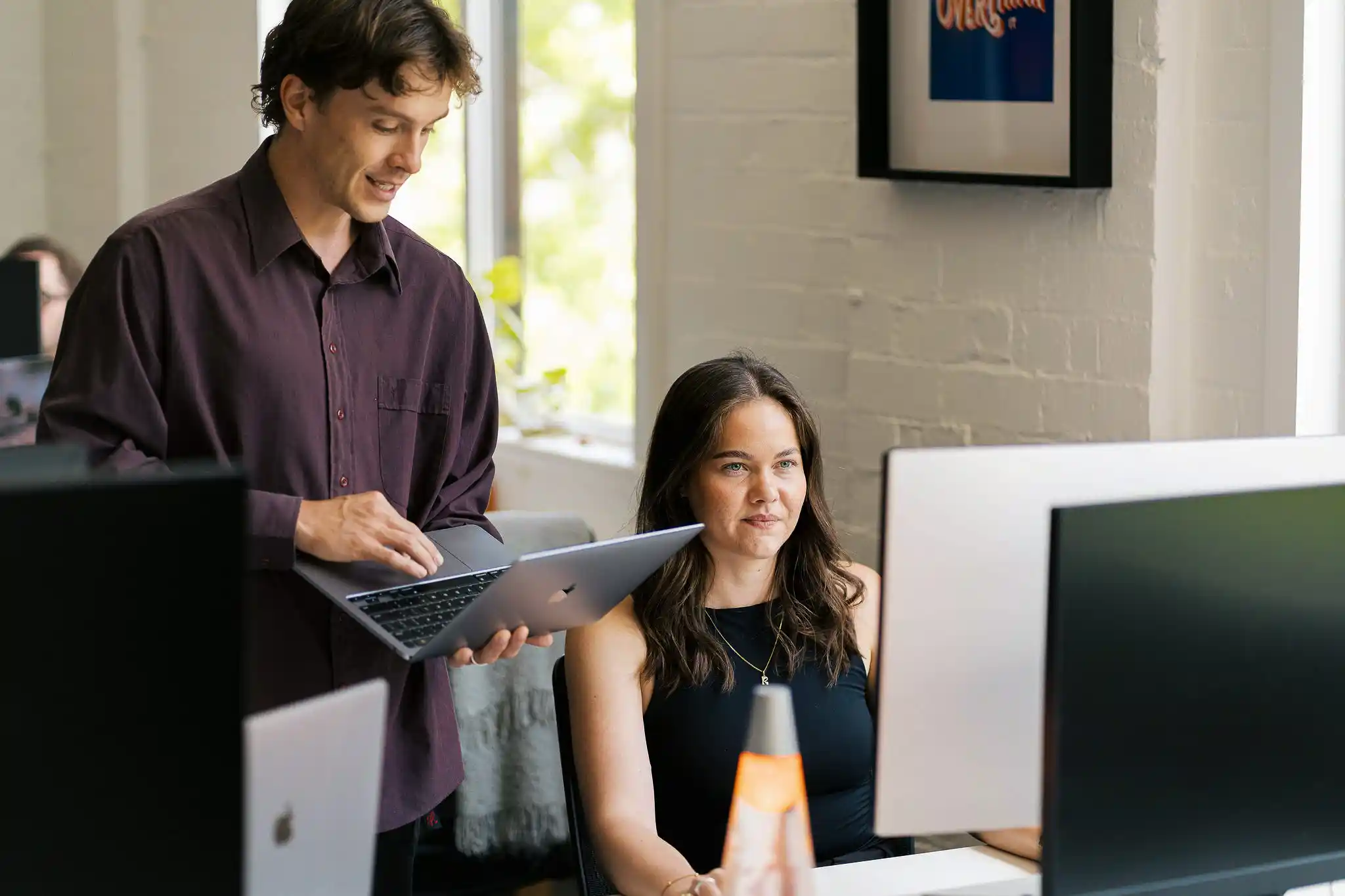 Two Start team members collaborating — a man reviewing documents while a woman observes, in a warm office setting
